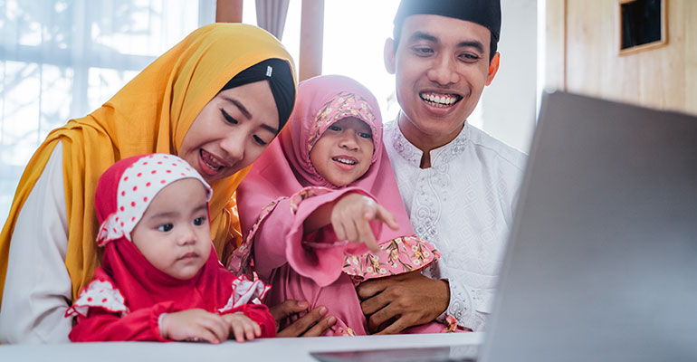 FPI Top 10 | Young family sat around a laptop laughing and smiling