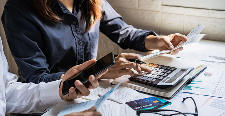 Couple sat with a calculator, bank cards and forms arranging finances